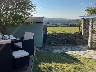 a garden with a table and chairs and a building at Moor View in Delabole