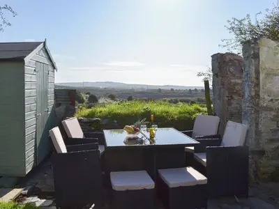 a table and chairs with drinks and a cat sitting on it at Moor View in Delabole