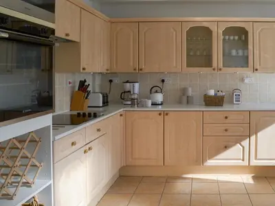a kitchen with wooden cabinets and white counter tops at Moor View in Delabole