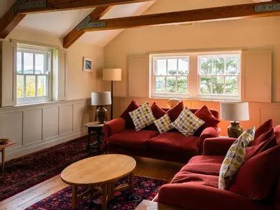 a living room with a red couch and two windows at Rosecott in St Ives