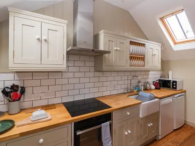 a kitchen with white cabinets and a sink at Rosecott in St Ives