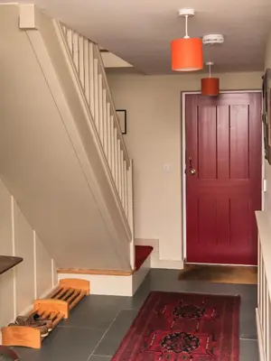 a hallway with a red door and a red rug at Rosecott in St Ives