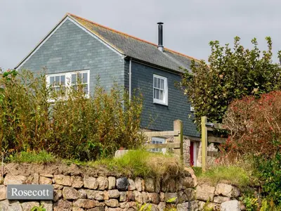 a blue house with a stone wall in front of it at Rosecott in St Ives