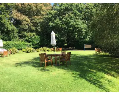 a table with chairs and an umbrella in the grass at Villa 7 Lanteglos, Camelford, Cornwall in Camelford