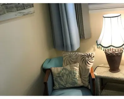 a lamp sitting on a table next to a chair at Villa 7 Lanteglos, Camelford, Cornwall in Camelford