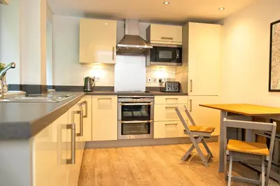 a kitchen with white cabinets and a wooden table at Fowey Landing in Fowey