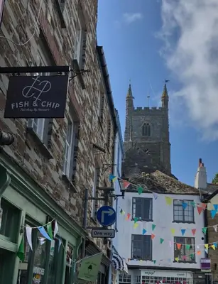 a street with buildings and a sign for a fish and club at Fowey Landing in Fowey