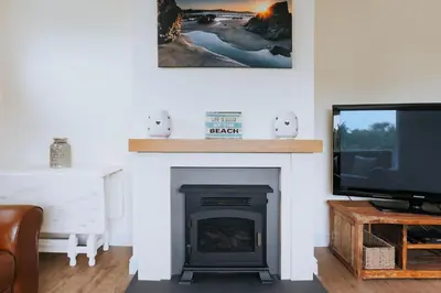 a living room with a fireplace and a tv at Sunset in Newquay