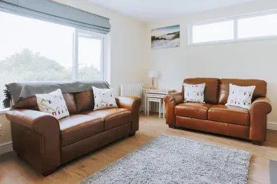 a living room with two leather couches and a rug at Sunset in Newquay