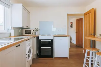 a white kitchen with a stove and a dishwasher at Sunset in Newquay