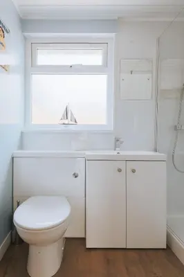 a white bathroom with a toilet and a window at Sunset in Newquay
