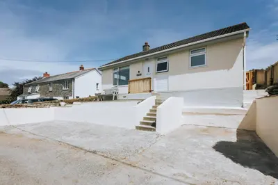 a house with a white fence in front of it at Sunset in Newquay