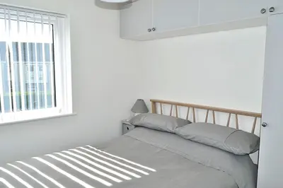 a bed in a white bedroom with a window at 2 Rosemullion in Perranporth