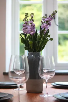 a table with two wine glasses and a vase with purple flowers at The Wood Shed in Truro