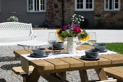 a wooden table with a vase of flowers and glasses at The Wood Shed in Truro