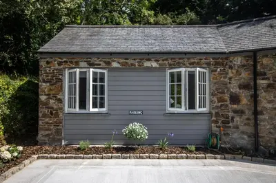 a small stone house with white windows and flowers at The Wood Shed in Truro