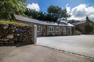 a stone building with a stone wall next to a driveway at The Wood Shed in Truro