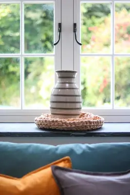 a vase sitting on a table in front of a window at The Wood Shed in Truro