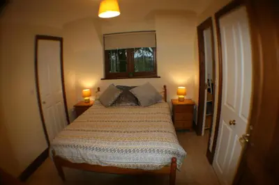 a bedroom with a large bed with two lamps on tables at Hooters Apartment EV Point in Wadebridge