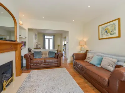 a living room with two leather couches and a fireplace at Beachcomber in Padstow