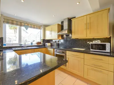 a kitchen with wooden cabinets and granite counter tops at Beachcomber in Padstow