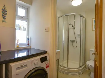a bathroom with a shower and a washing machine at Beachcomber in Padstow