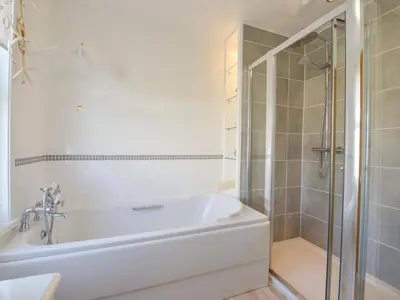 a white bathroom with a tub and a shower at Beachcomber in Padstow