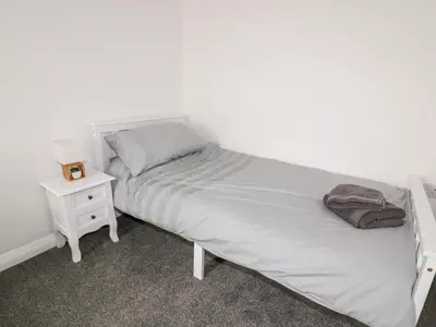 a bedroom with a white bed with a night stand at Fistral Quay in Newquay