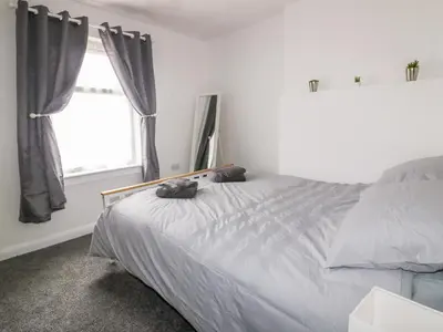a bedroom with a large bed and two windows at Fistral Quay in Newquay