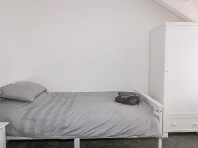 a bed in a white room with a white cabinet at Fistral Quay in Newquay