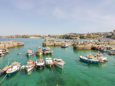 a group of boats are docked in a harbor at Fistral Quay in Newquay