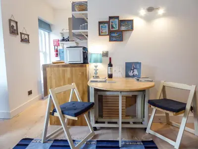 a small table and chairs in a room with a microwave at Harbour View Apartment in Looe