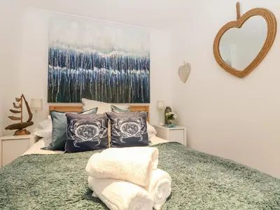 a bedroom with a bed with pillows and a mirror at Offshore in Porthtowan