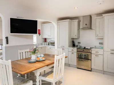 a kitchen with a wooden table and a television on the wall at Offshore in Porthtowan