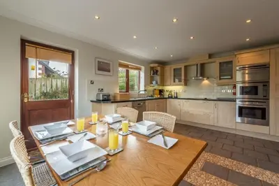 a large kitchen with a wooden table with chairs at The Summerhouse in Polzeath