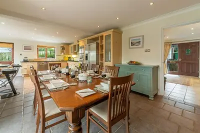 a kitchen and dining room with a wooden table and chairs at The Summerhouse in Polzeath