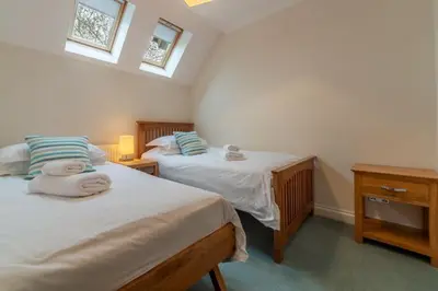 two twin beds in a room with two windows at The Summerhouse in Polzeath