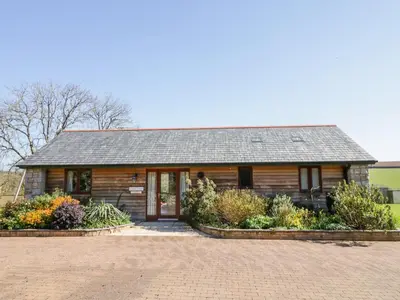 a log cabin with flowers in front of it at Kingcup Cottage in Saint Columb Major