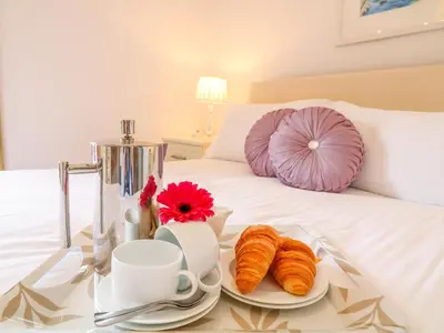 a tray with croissants and cups on a bed at Kingcup Cottage in Saint Columb Major