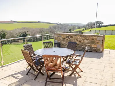 a table and chairs on a patio with a view at Kingcup Cottage in Saint Columb Major