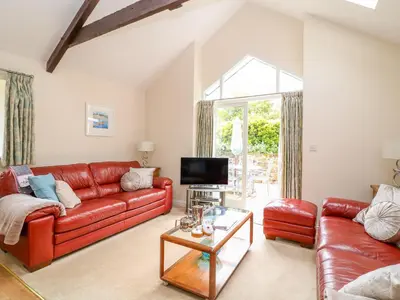 a living room with a red leather couch and a tv at FernGully in Saint Columb Major