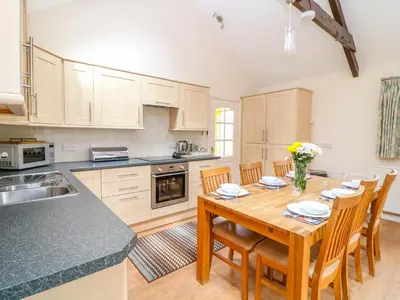 a kitchen with a wooden table and wooden chairs at FernGully in Saint Columb Major