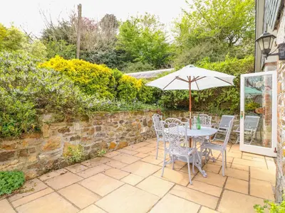 a table and chairs with an umbrella on a patio at FernGully in Saint Columb Major