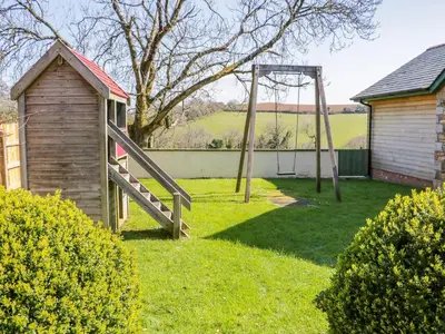 a playground in a yard with a wooden swing at FernGully in Saint Columb Major