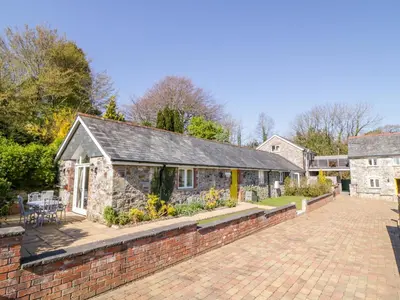 a stone house with a brick wall and a patio at FernGully in Saint Columb Major