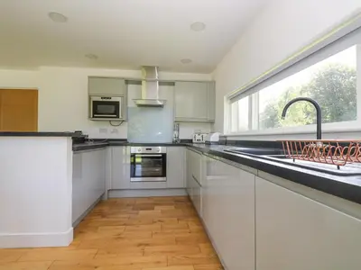 a kitchen with white cabinets and a large window at Willow in Truro