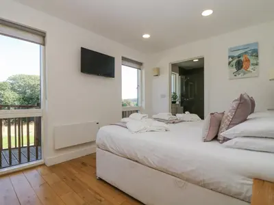 a white bedroom with a large bed and a balcony at Willow in Truro