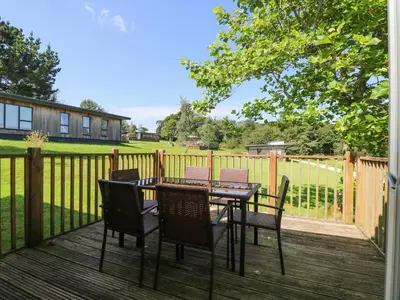 a table and chairs on a deck with a fence at Willow in Truro