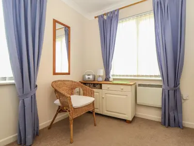 a bedroom with blue curtains and a chair and a desk at Deja Blue in Falmouth