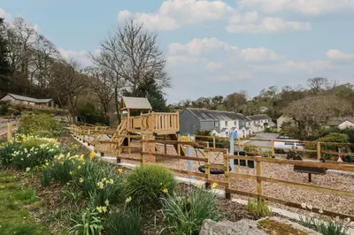 a wooden playground in a garden with flowers at Deja Blue in Falmouth